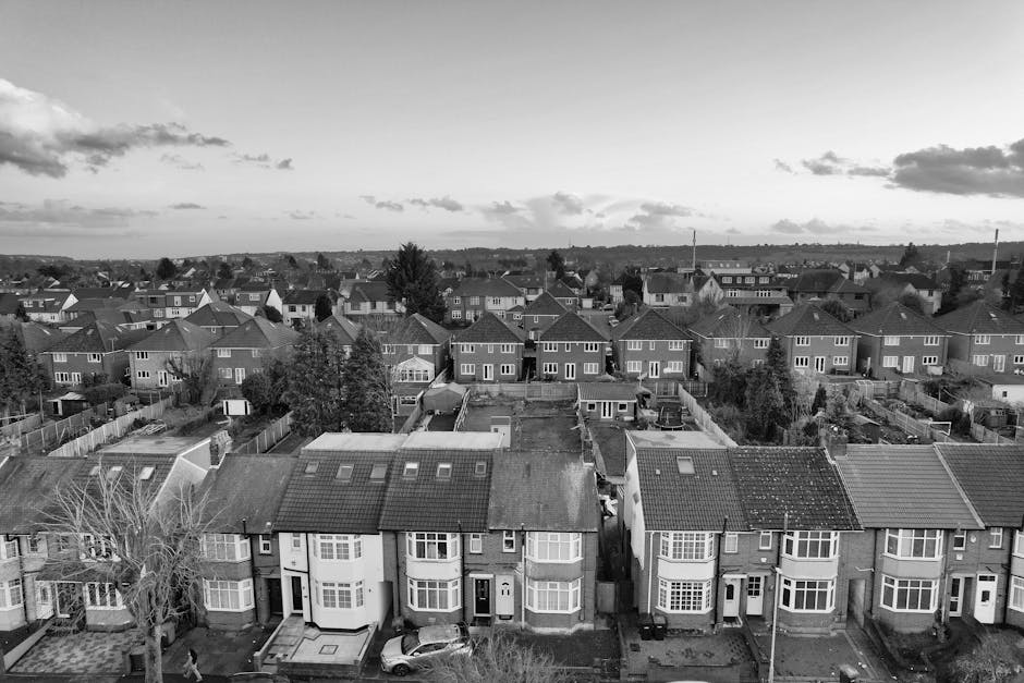 An aerial black-and-white photograph showing a residential street in Hampton Hill lined with terraced houses and detached homes. The street features parked cars on both sides, with a row of houses tha
